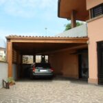 Tettoia in legno addossata alla casa con copertura in coppi e posto auto coperto